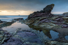 Purple Coloured Rocks On The Cornish Shoreline At Sunset, Polzeath, Cornwall, England