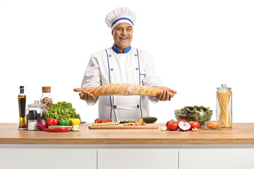 Poster - Mature male chef holding a baguette bread behind a kitceh counter