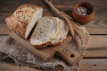 Wall Mural - Sliced fresh baked whole grain bread with oats, flax seeds and sesame seeds on rustic wooden board. Bakery products