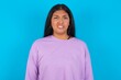 © Jihan - Portrait of dissatisfied Young beautiful hispanic woman wearing casual clothes over blue background smirks face, purses lips and looks with annoyance at camera, discontent hearing something unpleasant