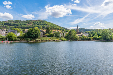 Wall Mural - Some houses at the shore of lake Rursee, In the middle of the Eifel National Park, surrounded by unique natural scenery and unspoilt nature