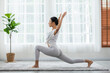 © 220 Selfmade studio - Happy Athletic Asian woman practice yoga stretching pose for stretching muscle for warm up with meditation smile,Healthy female doing yoga exercise and relax at home. Yoga self care Healthcare Concept