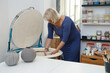 © ninelutsk - Woman artist putting ceramics into kiln. Raw pottery ready to be fired in oven. Ceramist working in studio making vases and plates. Clay modeling workshop
