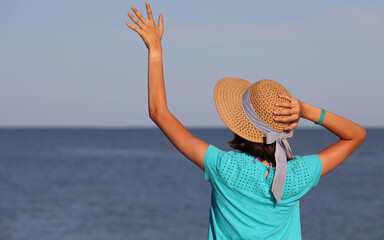 young girl with boater straw hat by the sea during summer vacation