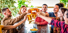 Happy Weekend. Group Of Friends Cheering Clincking Beer Glasses In A Pub Restaurant Celebrating Vacation Holidays. Interracial People Drinking Together On A Social Gathering. Joy, Lifestyle Concept