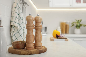 Poster - Wooden salt and pepper shakers, bowl with bay leaves on white countertop, space for text