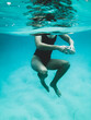 © Austockphoto - Mature woman's athletic body treading water from underwater perspective in ocean