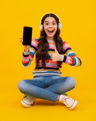 Canvas Print - Amazed teenager. Teenager child girl holding smartphone. Hipster girl types text message on cell phone, enjoys online communication, types feedback. Kid showing blank screen mobile phone, mockup.