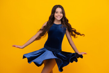 Happy girl face, positive and smiling emotions. Young graceful teenager child in fashion dress isolated on yellow background. Movement dress of young child girl. Beautiful teen in trendy clothing.