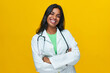 Cheerful young female doctor standing by a yellow background smiling looking camera, isolated Indian