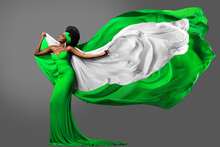 Woman Dancing With Nigerian Flag In Green White Dress. Fashion Model With Afro Hair In Long Gown With Flying Silk Scarf. Waving Chiffon Fabric Over Gray. Nigeria Independence Day