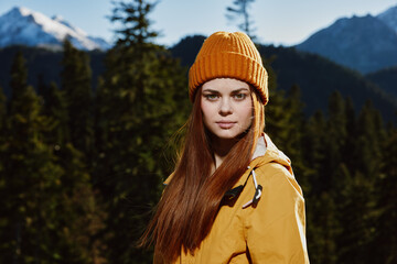 Canvas Print - Young woman tourist portrait in yellow raincoat traveling and hiking in the mountains. Hiking in nature in the sunset