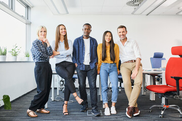 Successful diverse business people standing together at startup office. Multi-ethnic happy group of coworkers