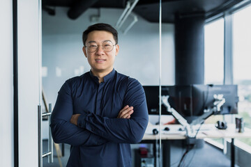 portrait of successful asian programmer, team leader company owner smiling and looking at camera wit