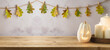 Wooden table with jack o lantern pumpkin and candles over autumn leaves garland background. Halloween holiday mock up for design and product display