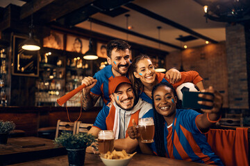 Wall Mural - Cheerful group of soccer fans taking selfie while having fun in pub.