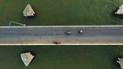 Canvas Print - Aerial view of a bridge over a river with people cycling