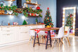 Christmas home room with Christmas tree and festive bokeh lighting, on background kitchen decorated for holiday . Christmas and new year interior-blurred background. Lots of lights that glow in dark.