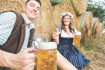 Wall Mural - Young woman and man with beer glass and pretzel on wooden background .Oktoberfest concept