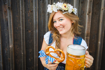 Wall Mural - Beautiful woman with pretzel in a traditional bavarian dirndl Oktoberfest.