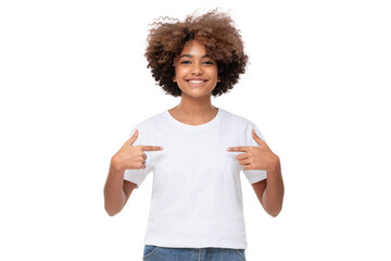 Smiling african girl pointing at her blank white tshirt with both index fingers, copy space for your ads, isolated