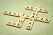 aging, time, lifespan and healthspan crossword in ivory letter tiles against textured handmade paper, age and longevity concept