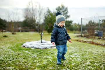 Canvas Print - Funny toddler boy having fun outdoors on chilly winter day. Child exploring nature.