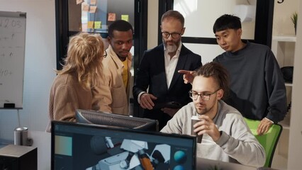 A multinational team of 3D game and application developers discussing a project at the computer in the company's studio.