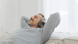 © eggeeggjiew - Happy relaxed Mature Adult man in headphones listening to the music and resting sitting on comfortable sofa in living room at home. Senior male sleeping on couch