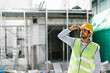 © thanmano - On the building construction site, Engineering worker with helmet and vest, using a radio to provide instructions
