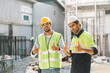 © thanmano - Working Safety at Workplace Concept, Two construction workman don safety jackets and helmets on construction site