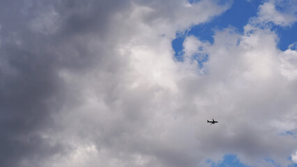 Wall Mural - The passenger airplane is flying far away in the dark clouds. Aircraft in the air. International passenger air transportation