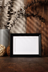 Fototapete - blank black photo frame with kitchenware on wood table with sunlight