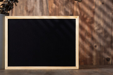 Fototapete - blank blackboard frame with kitchenware on wood table with sunlight