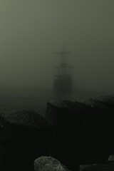 Wall Mural - Vertical shot of pirate ship entering the port on a foggy day