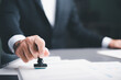 © chaylek - business people stamp On the contract documents at the desk, the concept of confirmation or approval of the agreement, the application authorization authority, the bank loan documents through support.