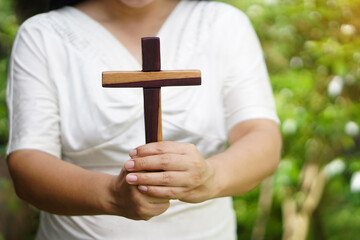 Closeup wooden cross that held by woman in white blouse. Concept : Christian worship.  Faith, forgiveness,belief, love and hope. Religious symbol of Christianity.