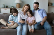© fizkes - Happy family taking selfie on home couch. Cheerful millennial parents and two little children using mobile phone for video call, laughing, relaxing with gadget on sofa. Communication concept
