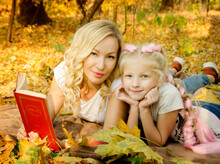 Beautiful Smiling Mother And Daughter Sitting On The Straw With Pumpkins In Jeans And White T-shirts On Halloween Party In Sunny Day. Family Look