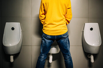 back Man peeing to toilet bowl in restroom