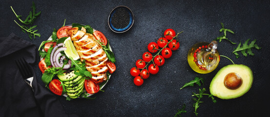 Wall Mural - Fresh vegetable salad with grilled chicken fillet, spinach, tomatoes, avocado, sesame seed and red onion on black background.. Healthy, detox, ketogenic diet food.. Top view banner