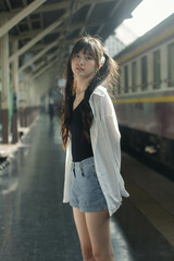 Wall Mural - Portrait of thai japan adult beautiful girl white shirt blue jeans relax time, train station fashion