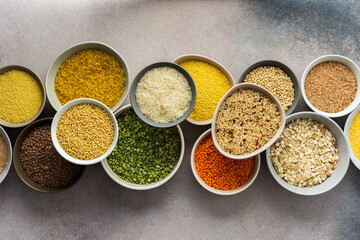 Various grain cereals in bowls on a light background, top view