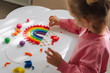 A little girl playing with rainbow from play dough for modeling. Art Activity for Kids. Fine motor skills. Sensory play for toddlers..