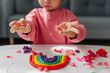 Child hands creating rainbow from play dough for modeling. Art Activity for Kids. Fine motor skills. Sensory play for toddlers.