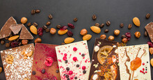 Handmade Chocolate With Berries, Nuts, Dried Fruits On A Dark Background. Black And White Chocolate. Chocolate Bar. Close-up. Chocolate Background. Culinary Background.