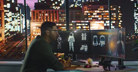 Male Engineer Developer of Space Suits and Space Gear Work in His Home Studio. Caucasian Latino Man Creating 3D VR Models of Spacesuits and Makes Corrections to Paper Sketches. Night City Background