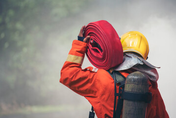 Firefighter Rescue training in fire fighting extinguisher. Firefighter fighting with flame using fire hose chemical water foam spray engine. Fireman wear hard hat, safety suit uniform for protection