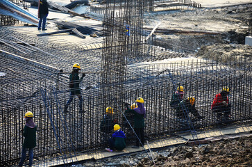 Wall Mural - Asian labor people and thai labour worker knitting metal rods bars into framework reinforcement for concrete pouring for working new structure building at site on January 19, 2014 in Bangkok, Thailand