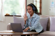 © itchaznong - Attractive smiling young woman on a video call by laptop at home